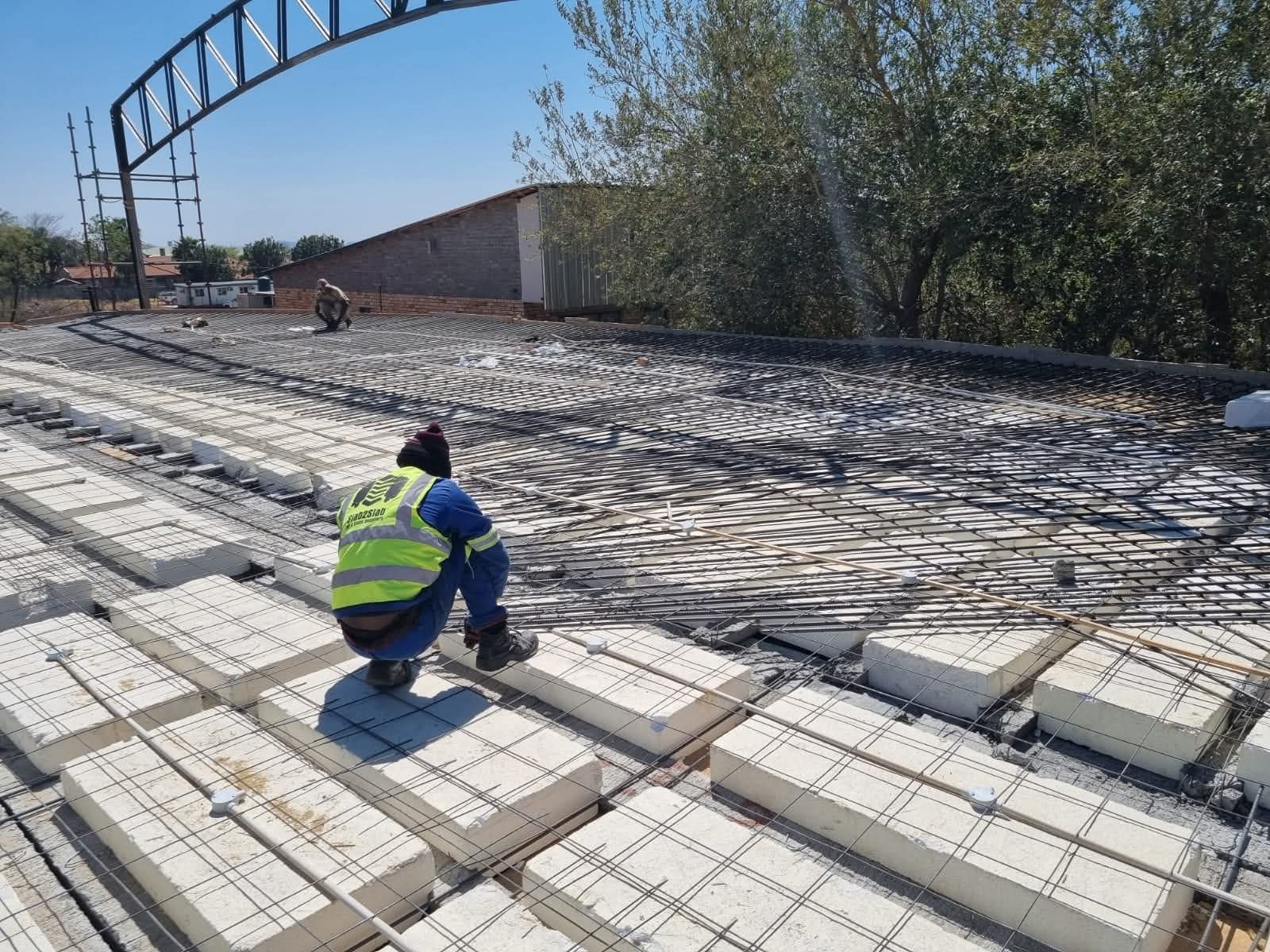 Worker laying polystyrene blocks during rib and block slab installation on a rooftop