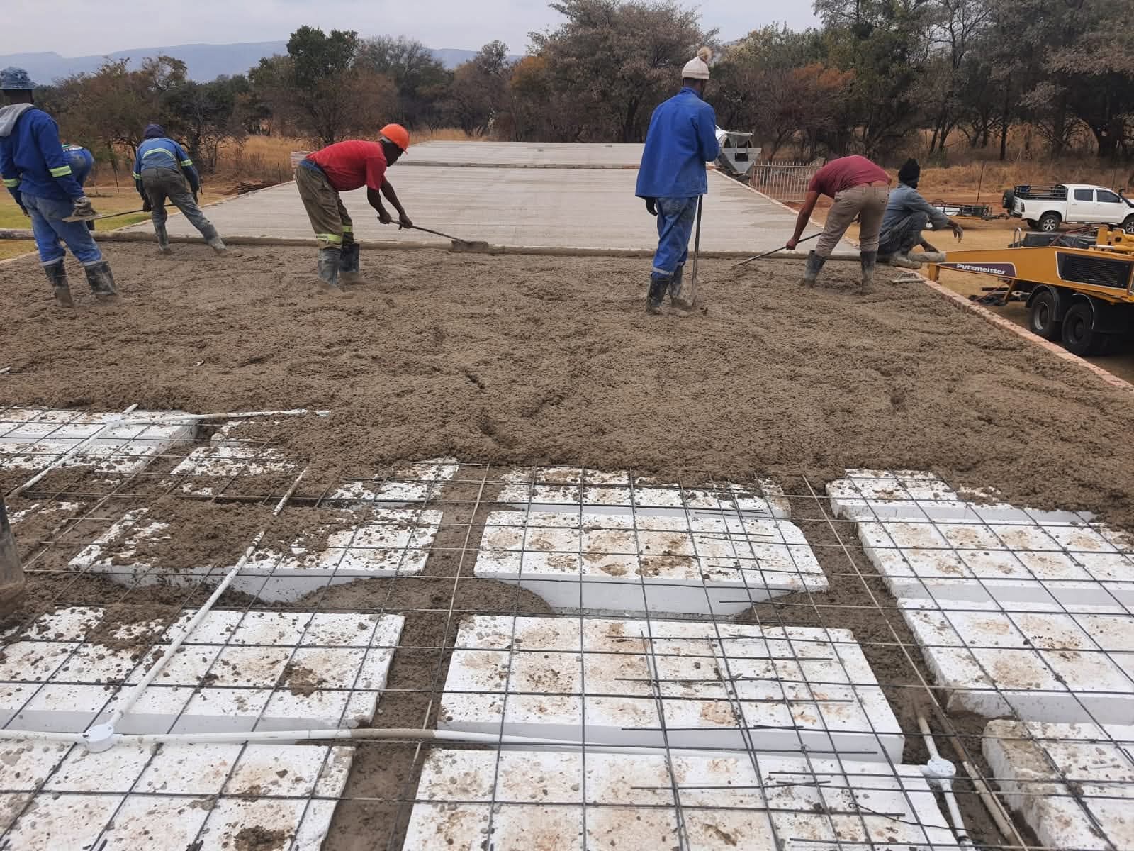 Workers screeding and finishing concrete topping on rib and block slab, Gauteng
