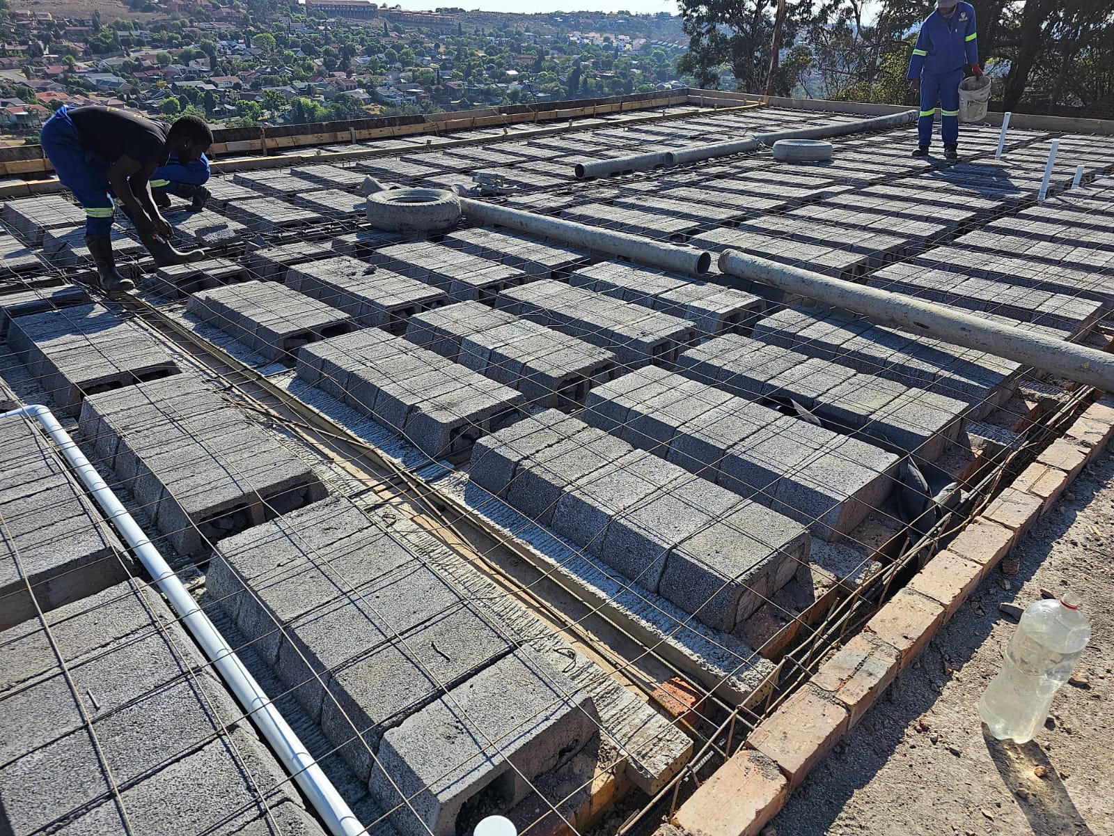 Workers installing rib and block slab on a rooftop with Johannesburg city in background